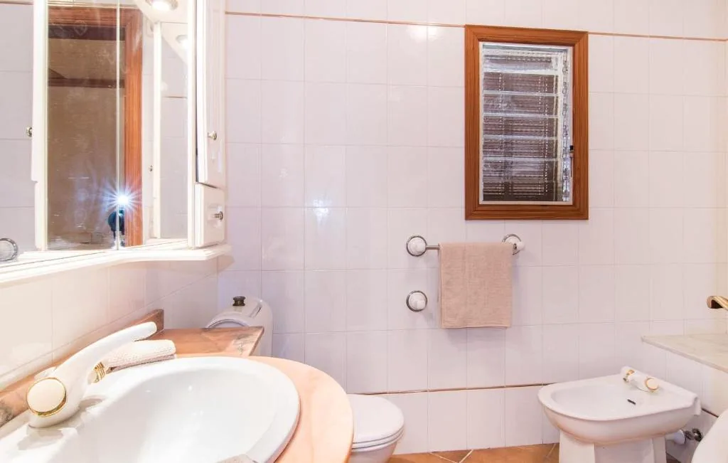Bright bathroom with sink, bidet, tiled walls, and wooden-framed window at Finca Bloom