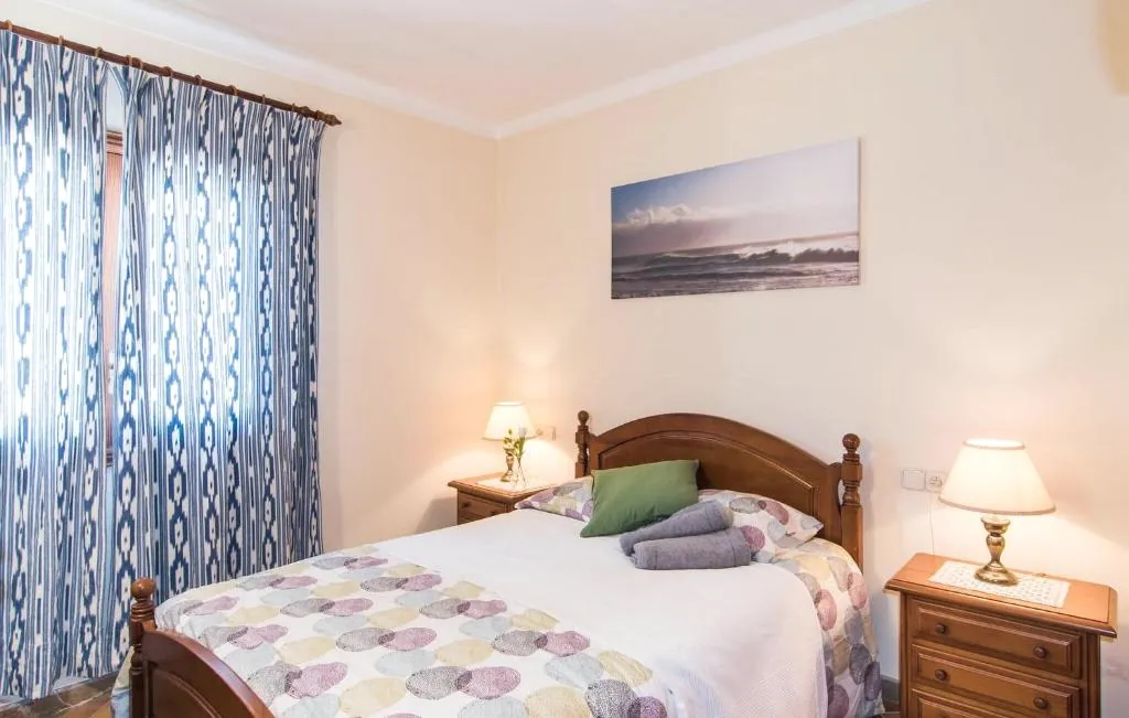 Double bedroom with blue curtains and warm natural light