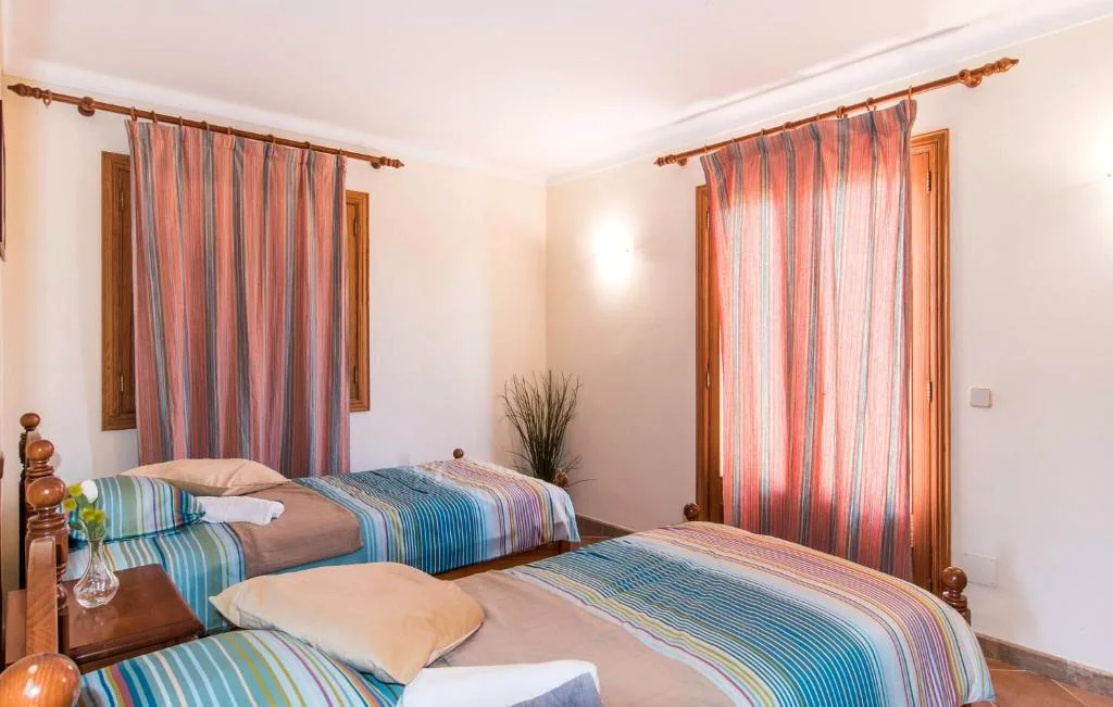 Bright twin bedroom with wooden beds, striped bedding, and soft natural light