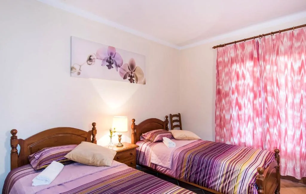 Twin bedroom with wooden beds, warm lighting, and pink striped curtains at Finca Bloom