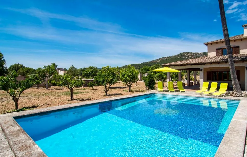 Swimming pool beside the orchard and terrace with Mallorcan hills in the background at Finca Bloom